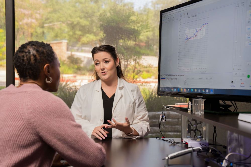 An audiologist talks to a patient about payment options for hearing aids. 