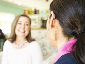 A woman with a hearing aid chats with a friend.